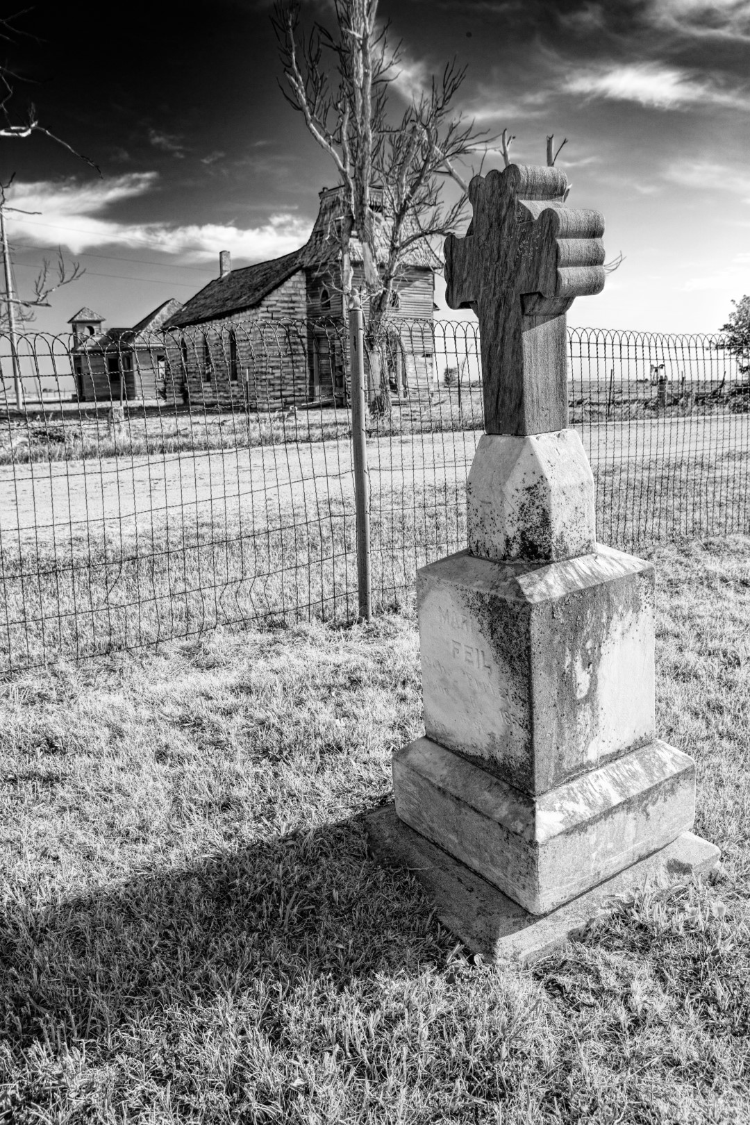 A headstone lies in solitude in front of an abandoned church near Dubuque Kansas