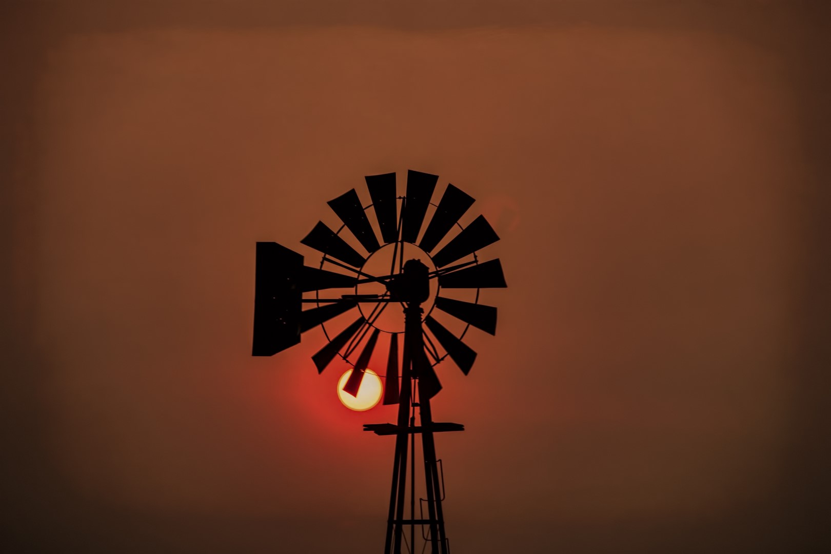The sun begins to set behind a windmill in Eastern Finney County Kansas