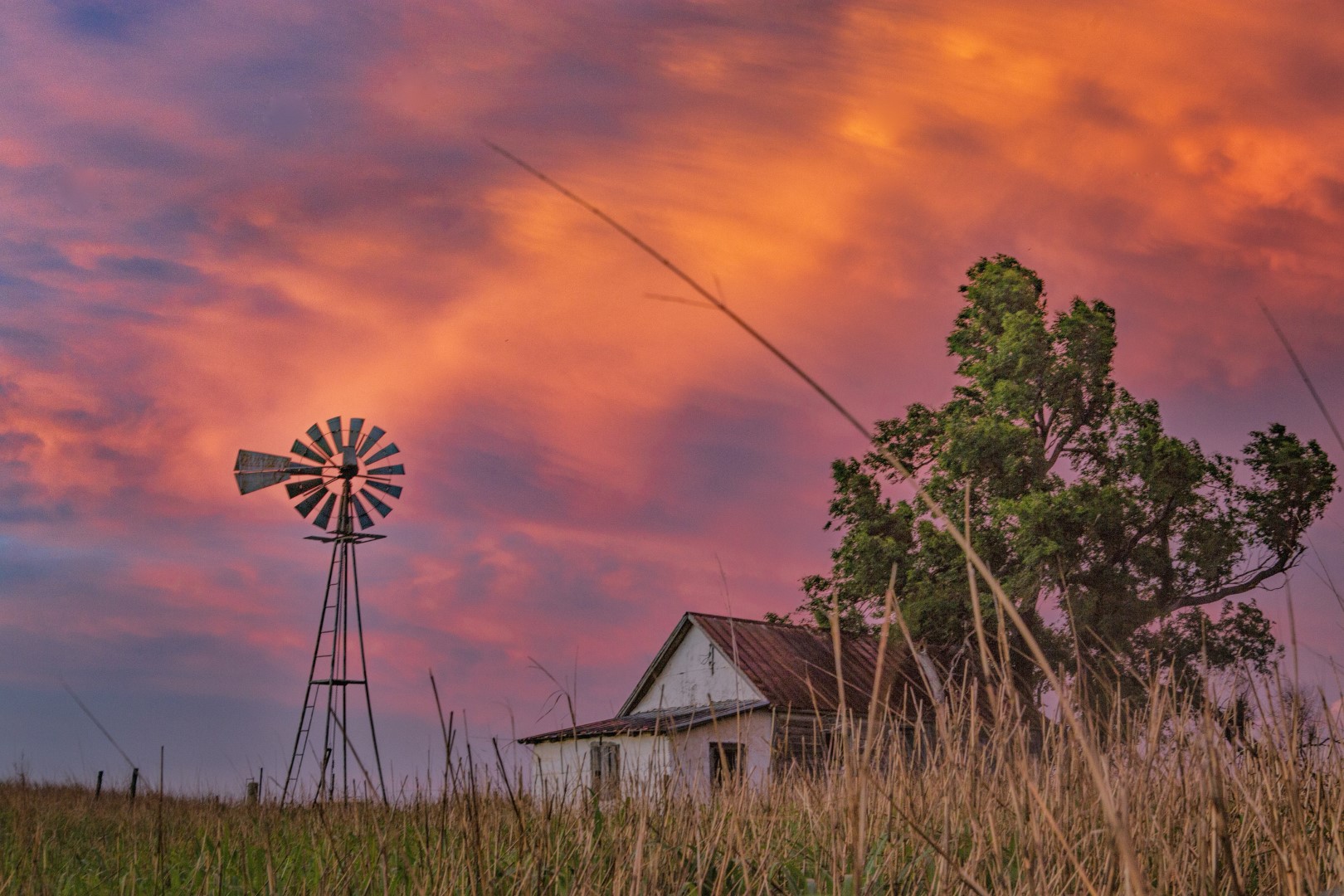 The backside of a dying thunderstorm is lit by the setting sun at an abandoned farmstead in Harper County Oklahoma
